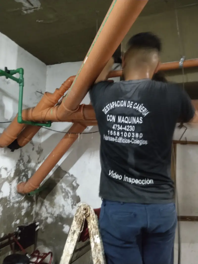 Técnico de Destapaciones OB realizando conexión de cañería cloacal aérea en subsuelo